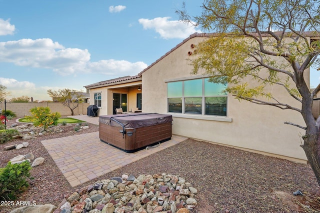 back of property with a hot tub and a patio area