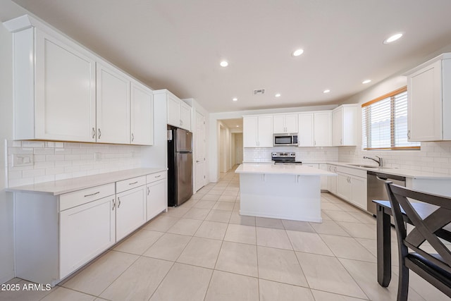 7648 W Kerby Ave, Phoenix, AZ 85043 - kitchen with stainless steel appliances, backsplash, a kitchen island, light countertops, and recessed lighting