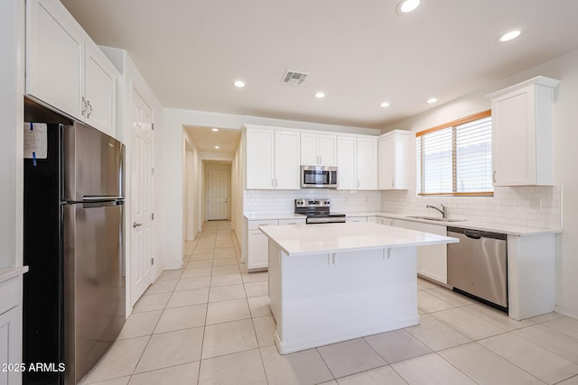7648 W Kerby Ave, Phoenix, AZ 85043 - kitchen with appliances with stainless steel finishes, a sink, decorative backsplash, a kitchen island, and light countertops