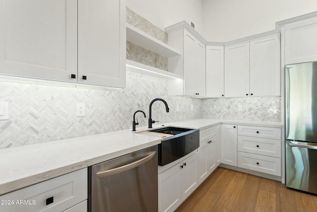 kitchen featuring light stone counters, stainless steel appliances, sink, white cabinets, and light hardwood / wood-style floors