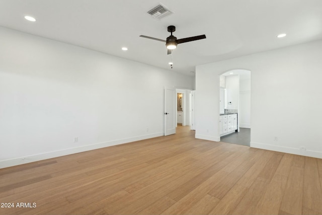 unfurnished bedroom featuring connected bathroom, ceiling fan, and light wood-type flooring