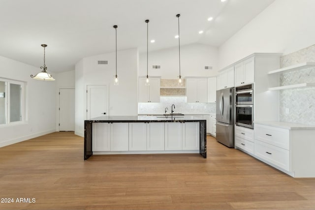 kitchen with pendant lighting, stainless steel appliances, white cabinetry, and light hardwood / wood-style flooring