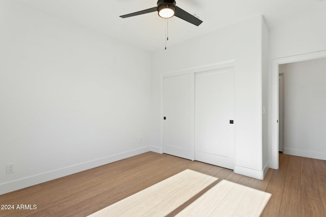 unfurnished bedroom featuring hardwood / wood-style flooring, ceiling fan, and a closet