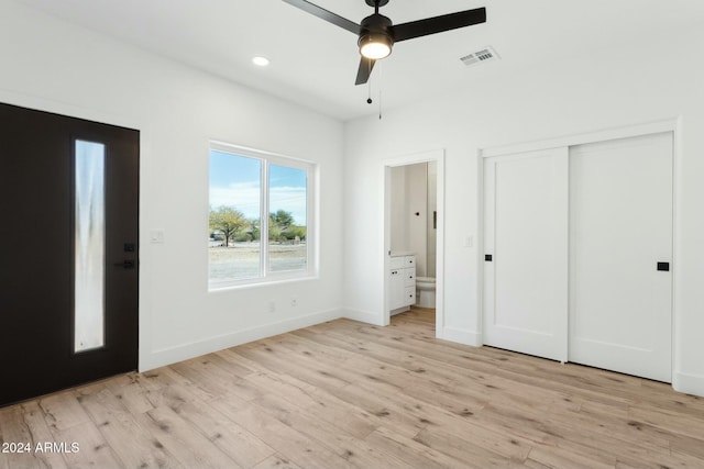 unfurnished bedroom with ensuite bathroom, a closet, ceiling fan, and light wood-type flooring