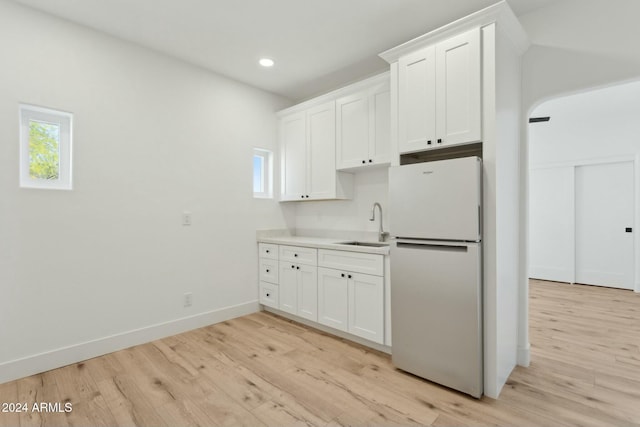 kitchen with white cabinetry, sink, light wood-type flooring, and white refrigerator