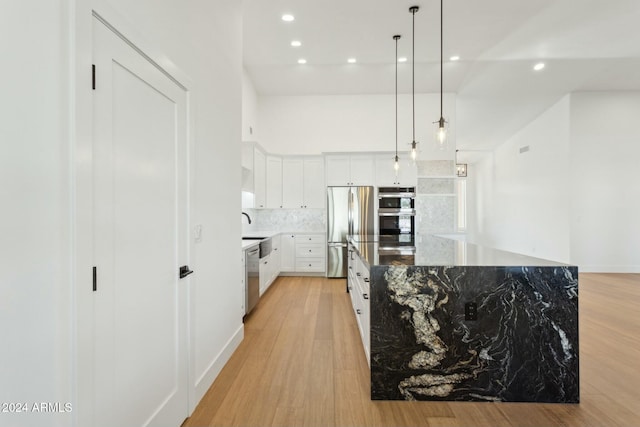 kitchen featuring a center island, hanging light fixtures, stainless steel appliances, white cabinets, and light wood-type flooring