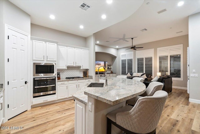 kitchen featuring light hardwood / wood-style floors, appliances with stainless steel finishes, light stone countertops, ceiling fan, and white cabinets