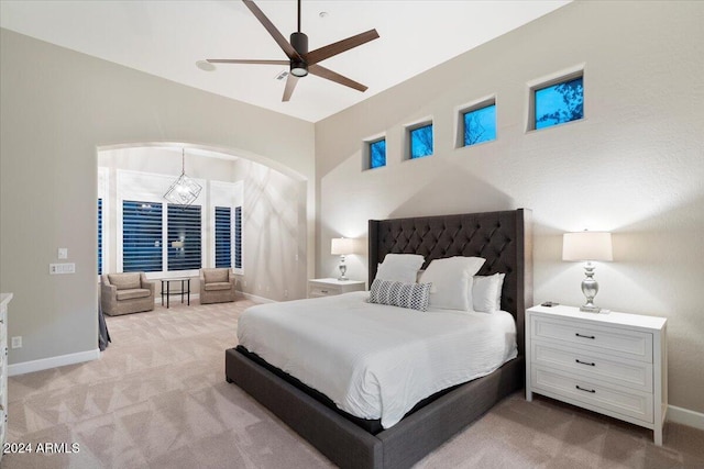 carpeted bedroom featuring ceiling fan with notable chandelier