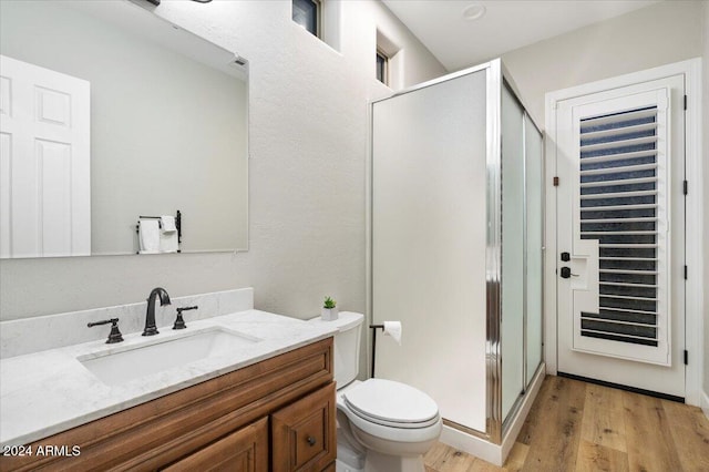 bathroom with vanity, hardwood / wood-style flooring, toilet, and a shower with door