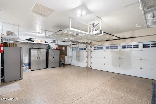 garage with stainless steel fridge and a garage door opener