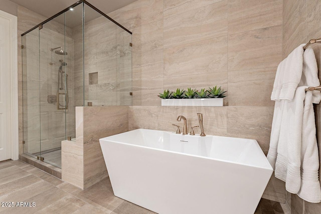 full bath featuring a freestanding tub, a shower stall, and tile walls