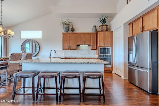 kitchen with brown cabinets, a kitchen bar, stainless steel appliances, and a sink