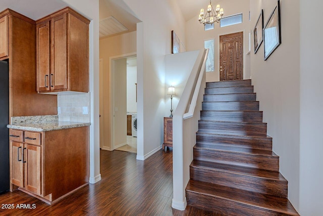 stairs with a chandelier, washer / dryer, baseboards, and wood finished floors