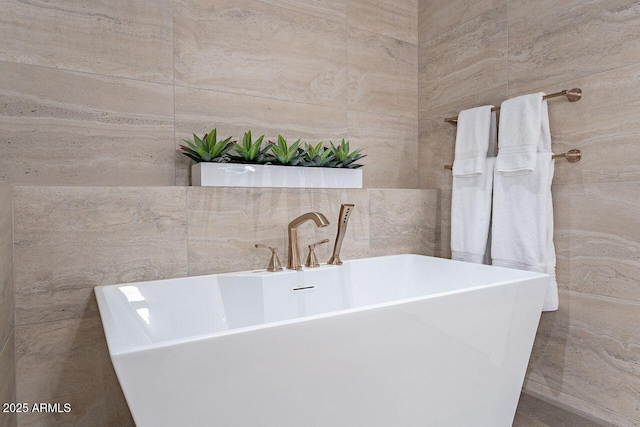 bathroom with a freestanding tub and tile walls