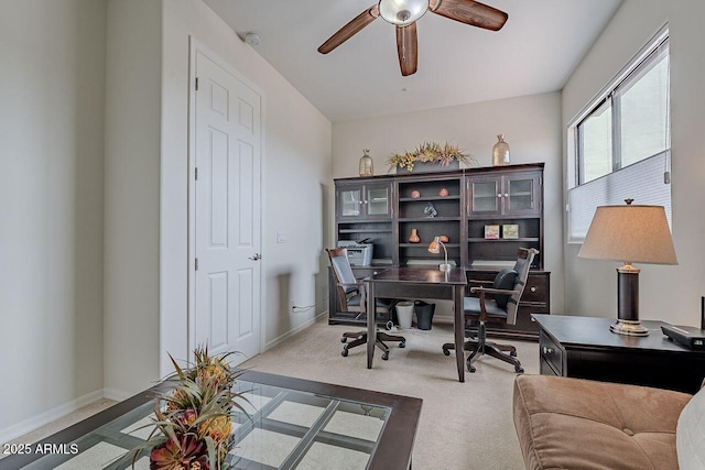 carpeted home office with ceiling fan and baseboards