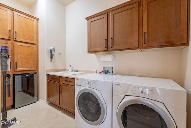 washroom with light tile patterned floors, washer and clothes dryer, a sink, and cabinet space