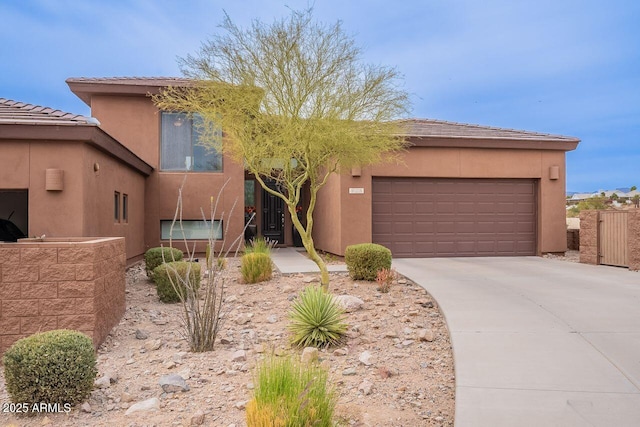 adobe home with a garage, concrete driveway, and stucco siding