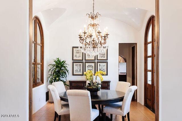 dining area with a chandelier, lofted ceiling, and light tile floors