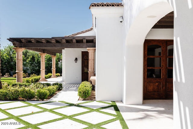 property entrance with a pergola, french doors, and a patio