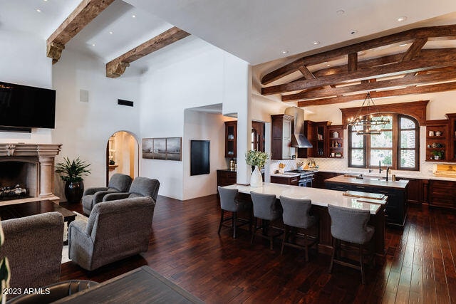 kitchen with beam ceiling, dark brown cabinetry, dark hardwood / wood-style floors, and an inviting chandelier