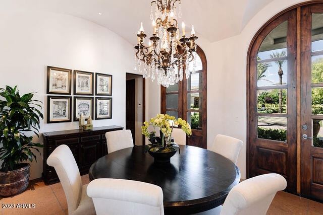 tiled dining space with lofted ceiling and a chandelier