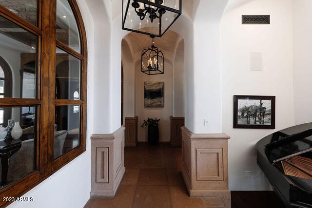 hall with a notable chandelier and dark tile floors