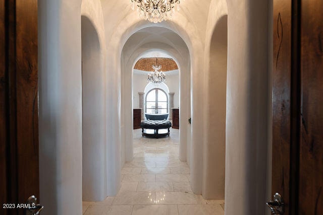 corridor featuring light tile flooring and a notable chandelier