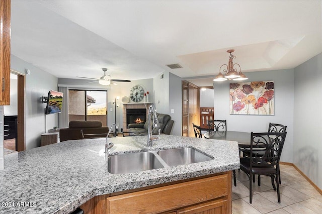 kitchen with light stone countertops, sink, ceiling fan, and decorative light fixtures