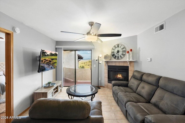 living room featuring ceiling fan, light tile patterned floors, and a tile fireplace