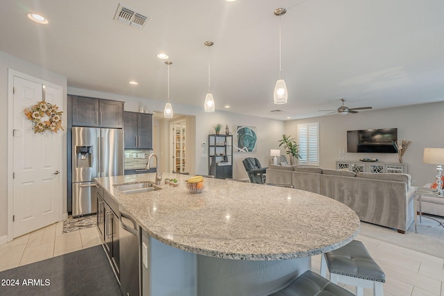 kitchen featuring ceiling fan, sink, hanging light fixtures, light stone counters, and appliances with stainless steel finishes