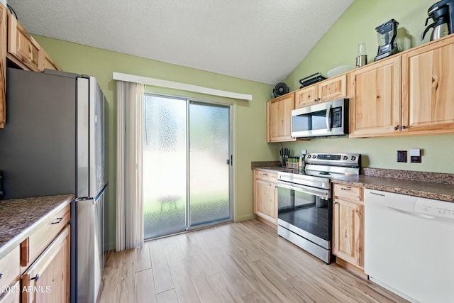 kitchen with dark countertops, appliances with stainless steel finishes, light wood-style floors, light brown cabinets, and a textured ceiling