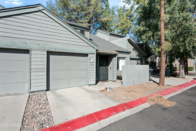 view of front facade with a garage, concrete driveway, and a shingled roof