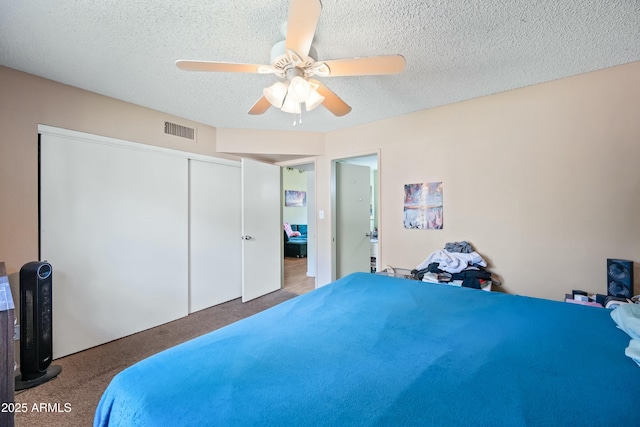 bedroom featuring a textured ceiling, ceiling fan, carpet floors, visible vents, and a closet