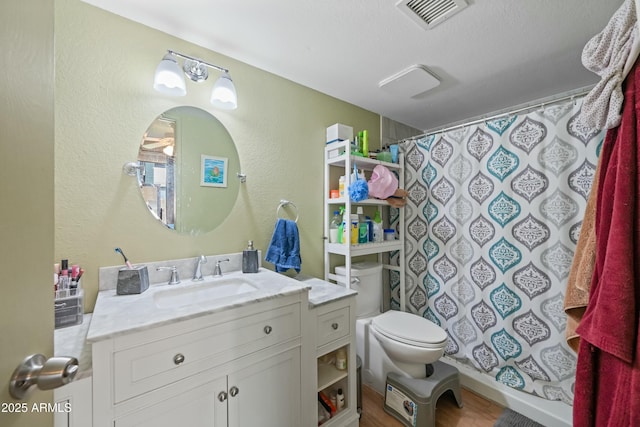 bathroom featuring visible vents, a textured wall, toilet, a shower with shower curtain, and vanity