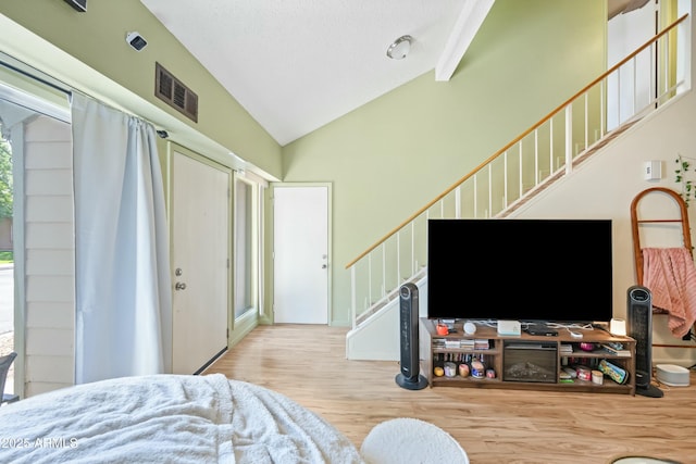 bedroom with high vaulted ceiling, visible vents, and wood finished floors