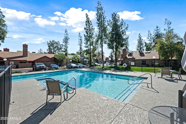 community pool featuring a residential view, fence, and a patio