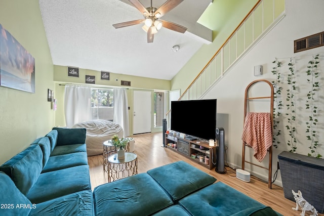 living room with a ceiling fan, visible vents, vaulted ceiling, and wood finished floors