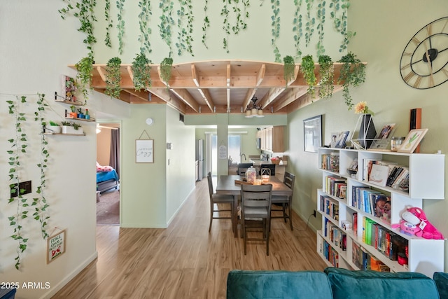 dining area with beam ceiling, baseboards, and wood finished floors