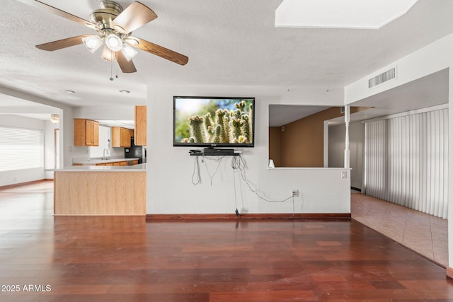 unfurnished living room featuring ceiling fan, sink, a textured ceiling, and dark hardwood / wood-style flooring