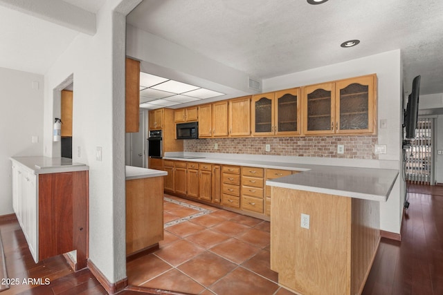 kitchen featuring decorative backsplash, wood-type flooring, black appliances, and kitchen peninsula