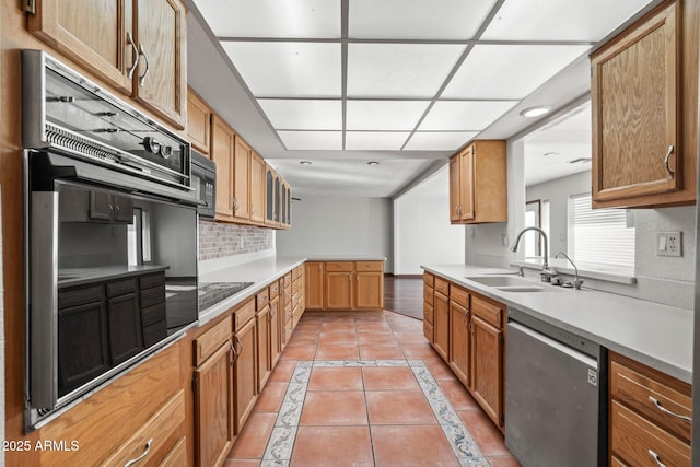 kitchen with tasteful backsplash, sink, light tile patterned floors, and black appliances