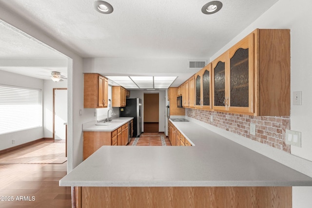 kitchen featuring sink, ceiling fan, black appliances, decorative backsplash, and kitchen peninsula