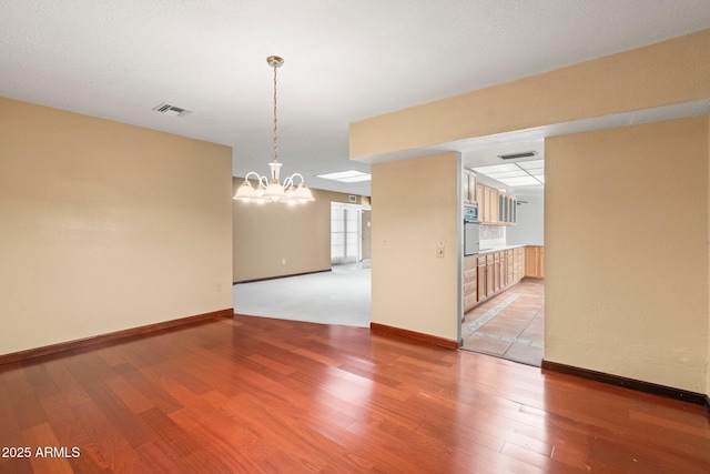 empty room featuring an inviting chandelier and wood-type flooring