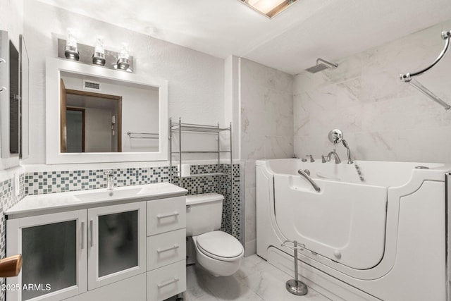 bathroom with a washtub, vanity, tile walls, and toilet