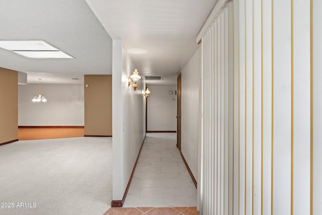 hall with light carpet, a skylight, and a chandelier