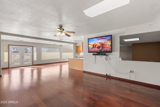 unfurnished living room with ceiling fan, hardwood / wood-style floors, a textured ceiling, and french doors