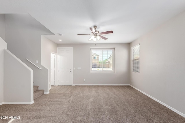 unfurnished living room featuring baseboards, stairs, and a ceiling fan