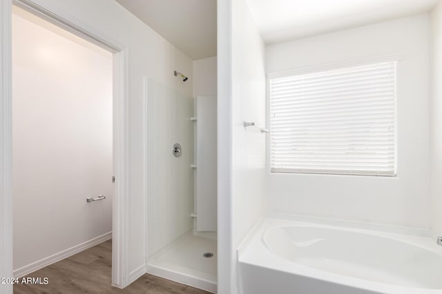 full bath with wood finished floors, a bath, baseboards, and walk in shower