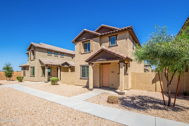 mediterranean / spanish-style house featuring stucco siding, fence, and a tiled roof