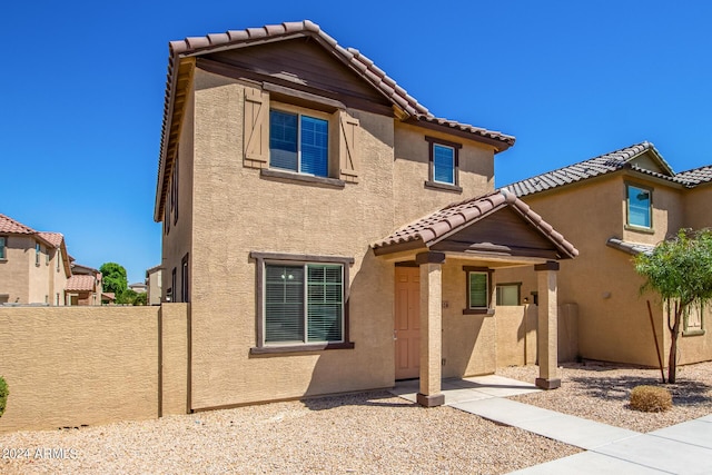 view of front of house with fence, stucco siding, and a tiled roof